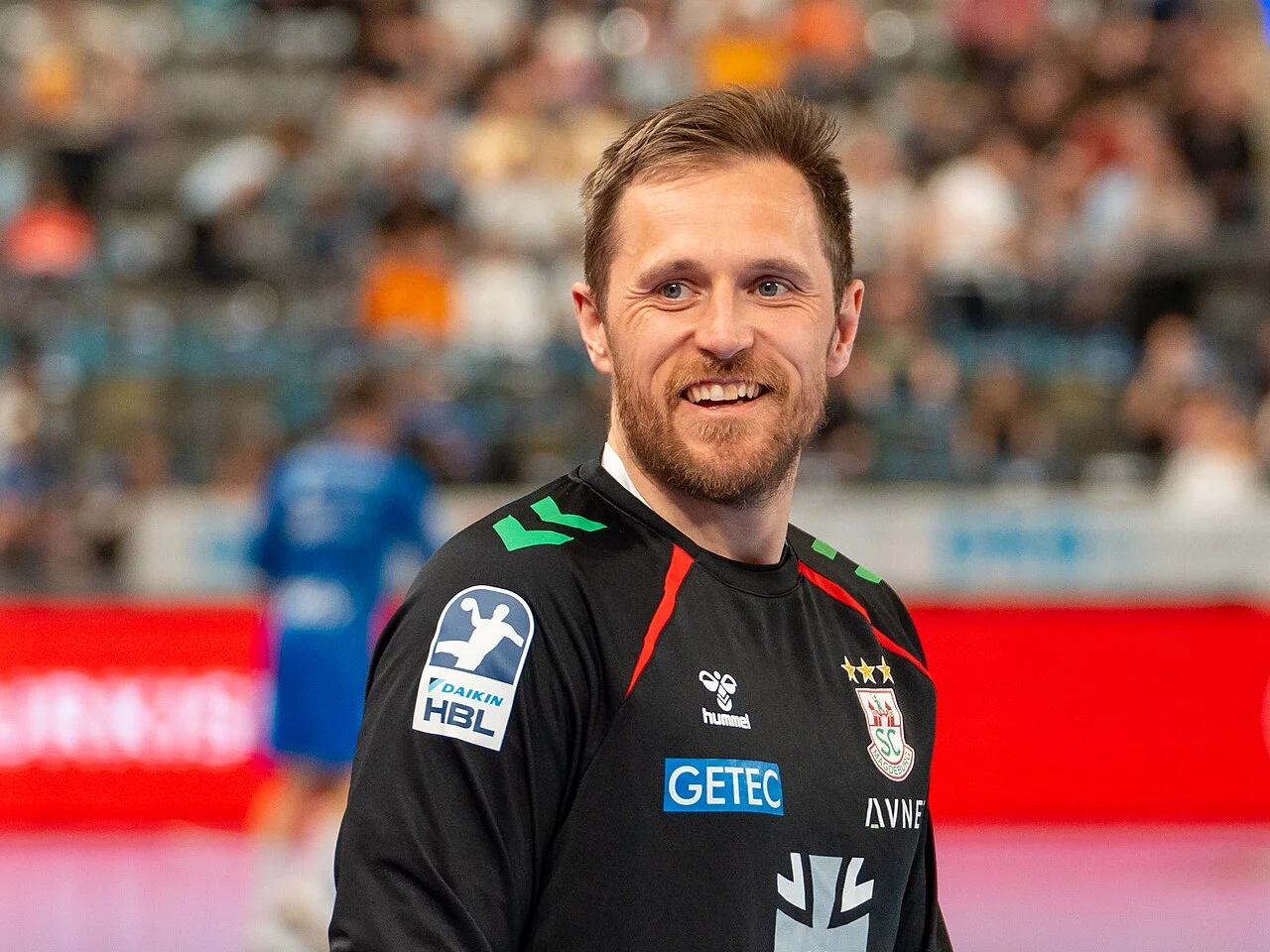 Albin Lagergren ler i SC Magdeburgs svarta tröja i en handbollshall.